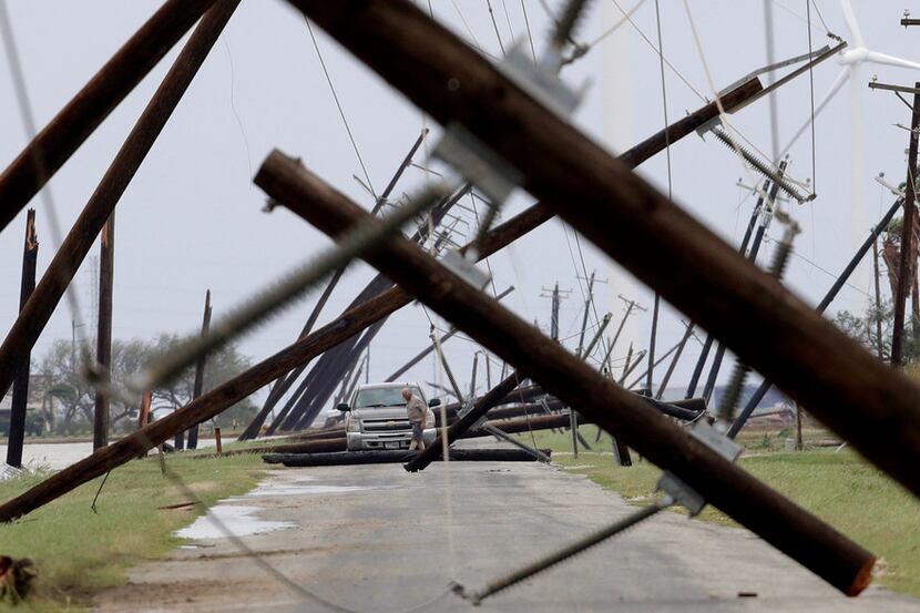 On Aug. 26, a driver works his way through a maze of fallen utility poles damaged in the...