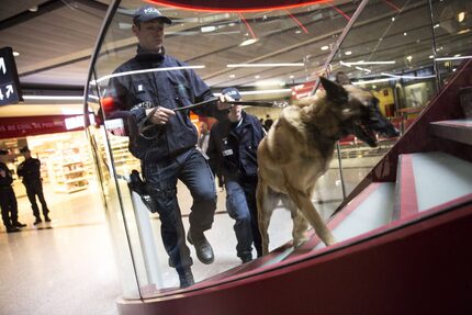  French police officers and a sniffer dog patrol a terminal building at Charles de Gaulle...