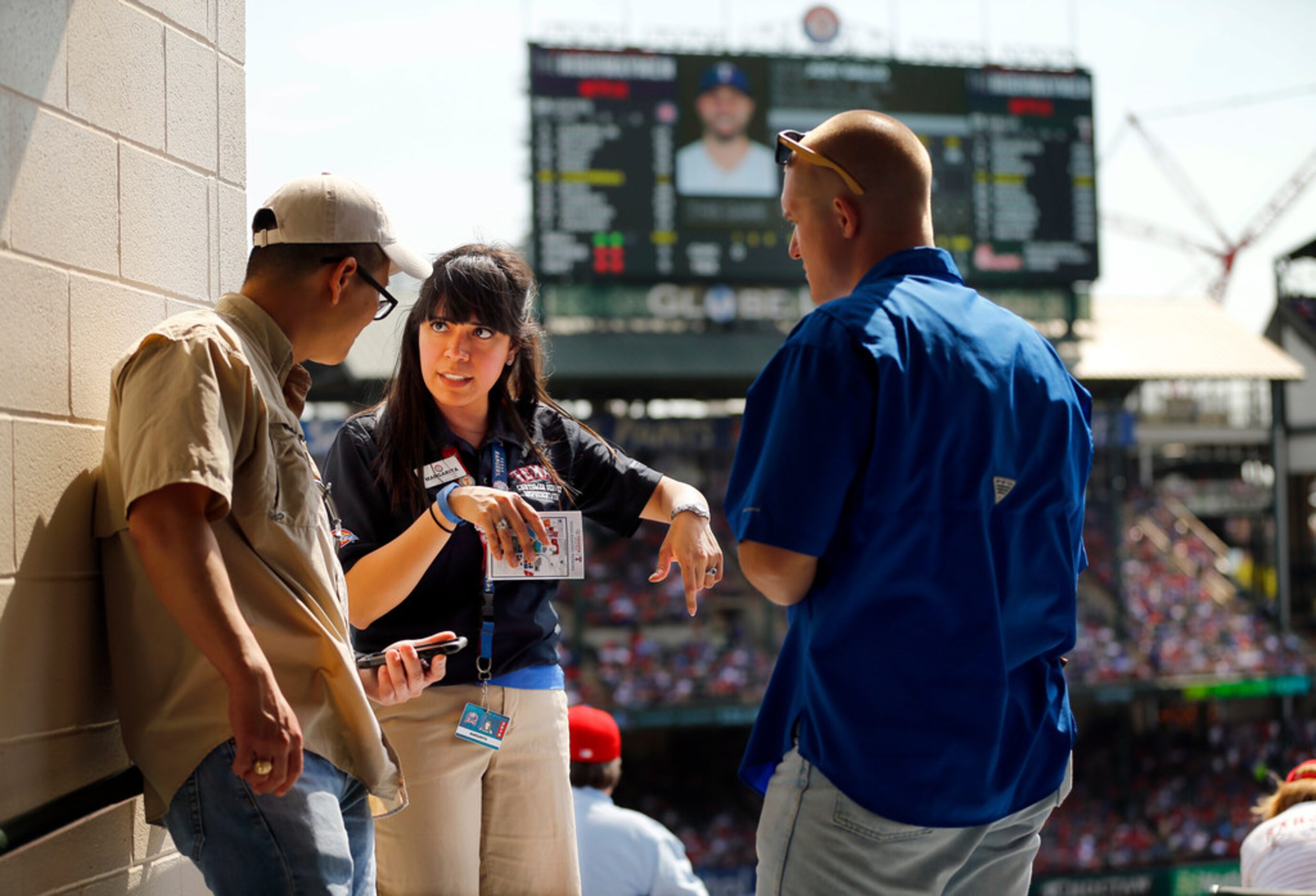 Texas Rangers usher Margarita Aguirre (center) helps fans Leland Tieh of Frisco (left) and...