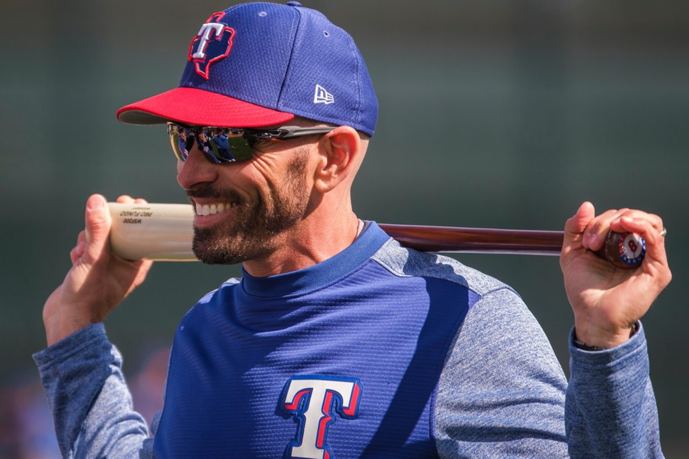 Texas Rangers manager Chris Woodward smiles while watching batting practice during the first...