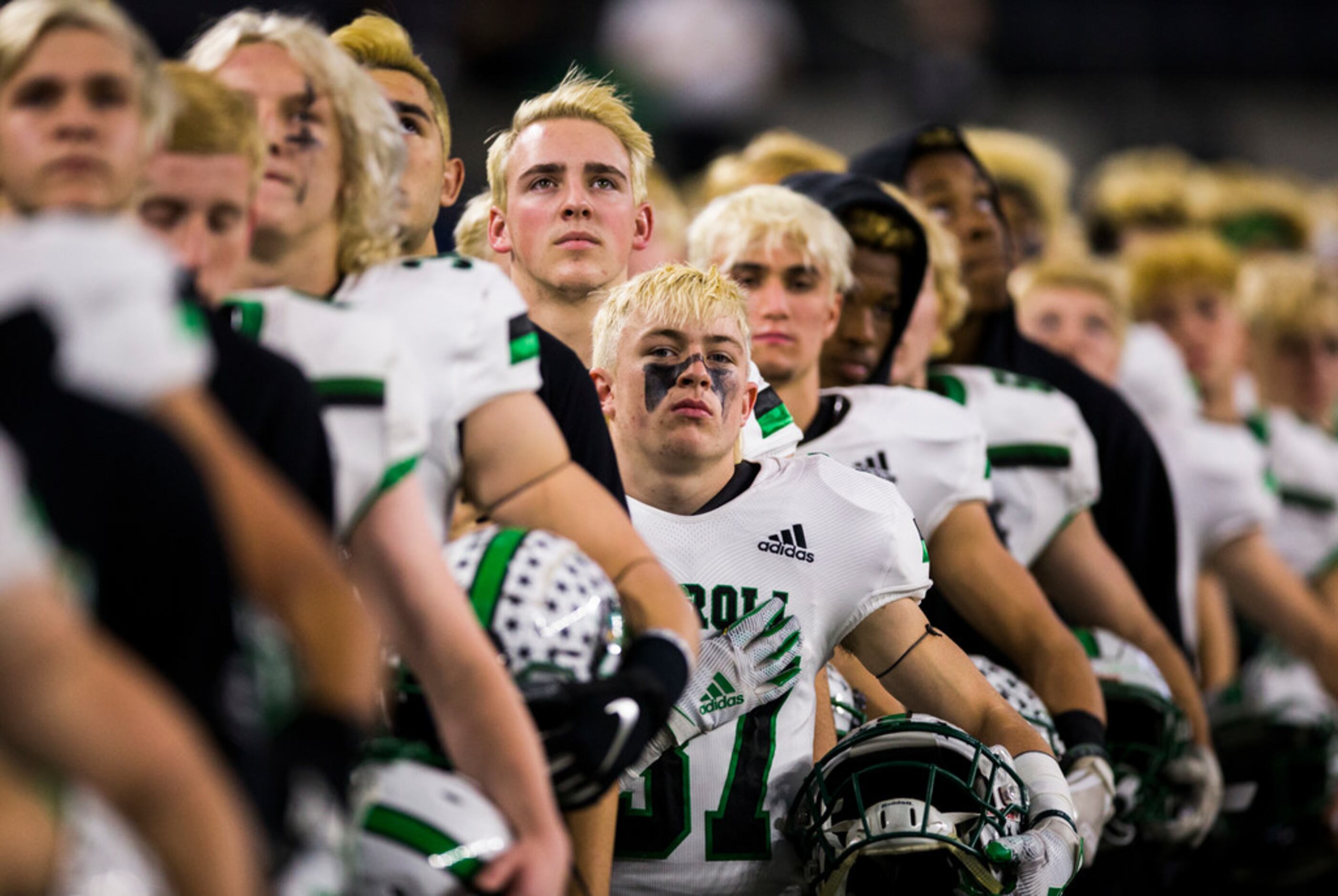 Southlake Carroll football players listen to the national anthem before a Class 6A Division...