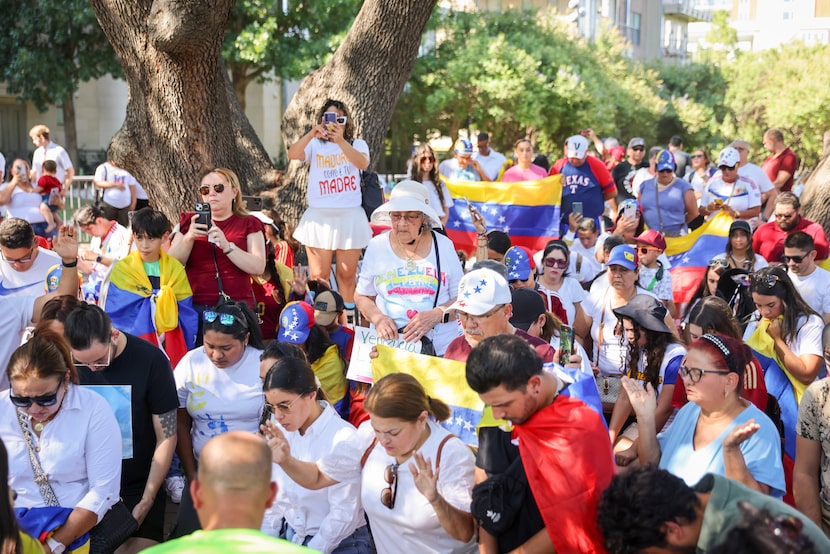 Venezuelan supporters kneel down to pray during a protest against the official election...