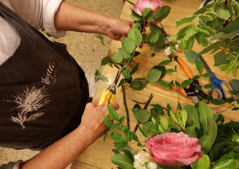 Thistle Floral Design owner Jan Barstad trims the stems of flowers.