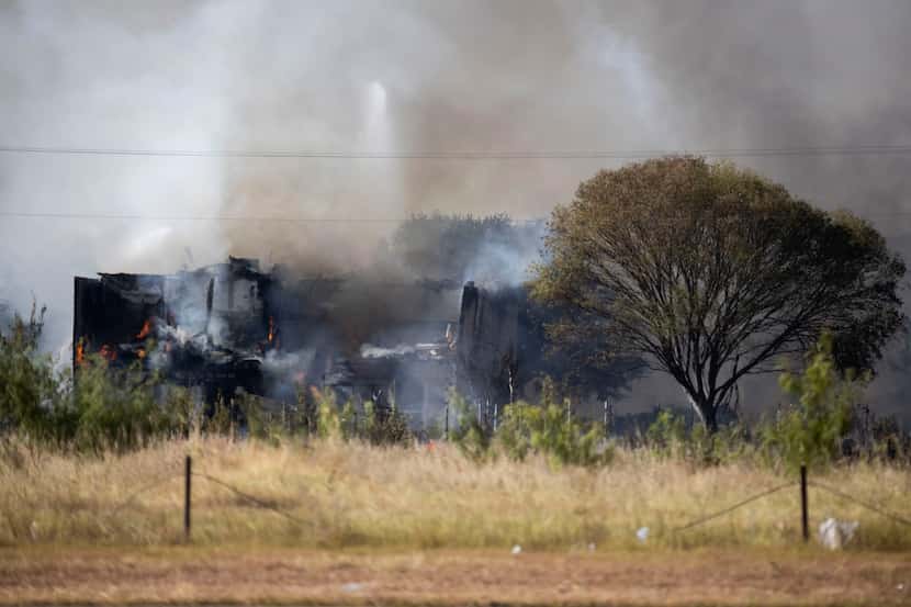 Smoke rises from the ashes after firefighters extinguished a large grass fire that spread...