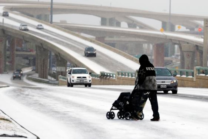 A man pushes an empty stroller earlier this month on a snow covered street in Dallas. North...