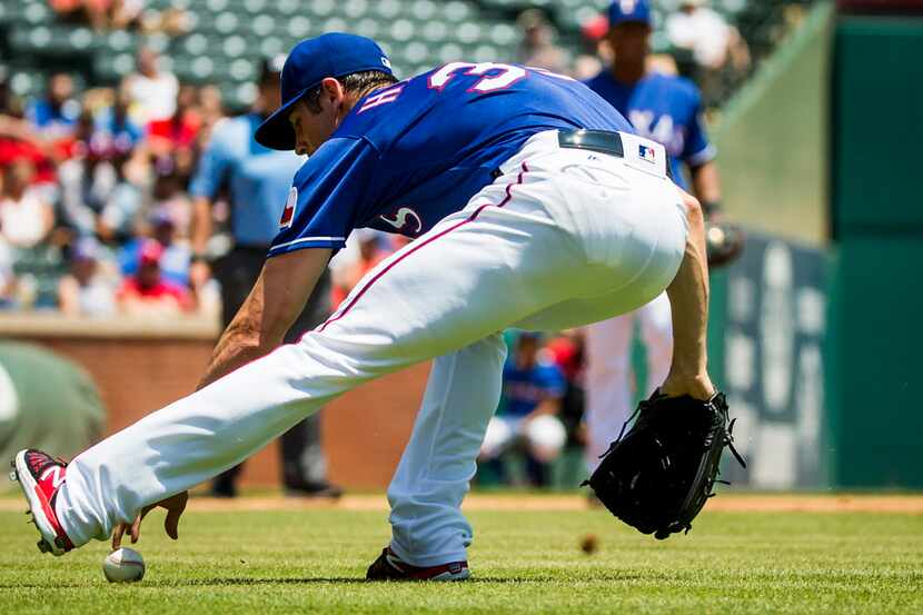 Texas Rangers starting pitcher Cole Hamels fields a ball that was hit off his glove by...