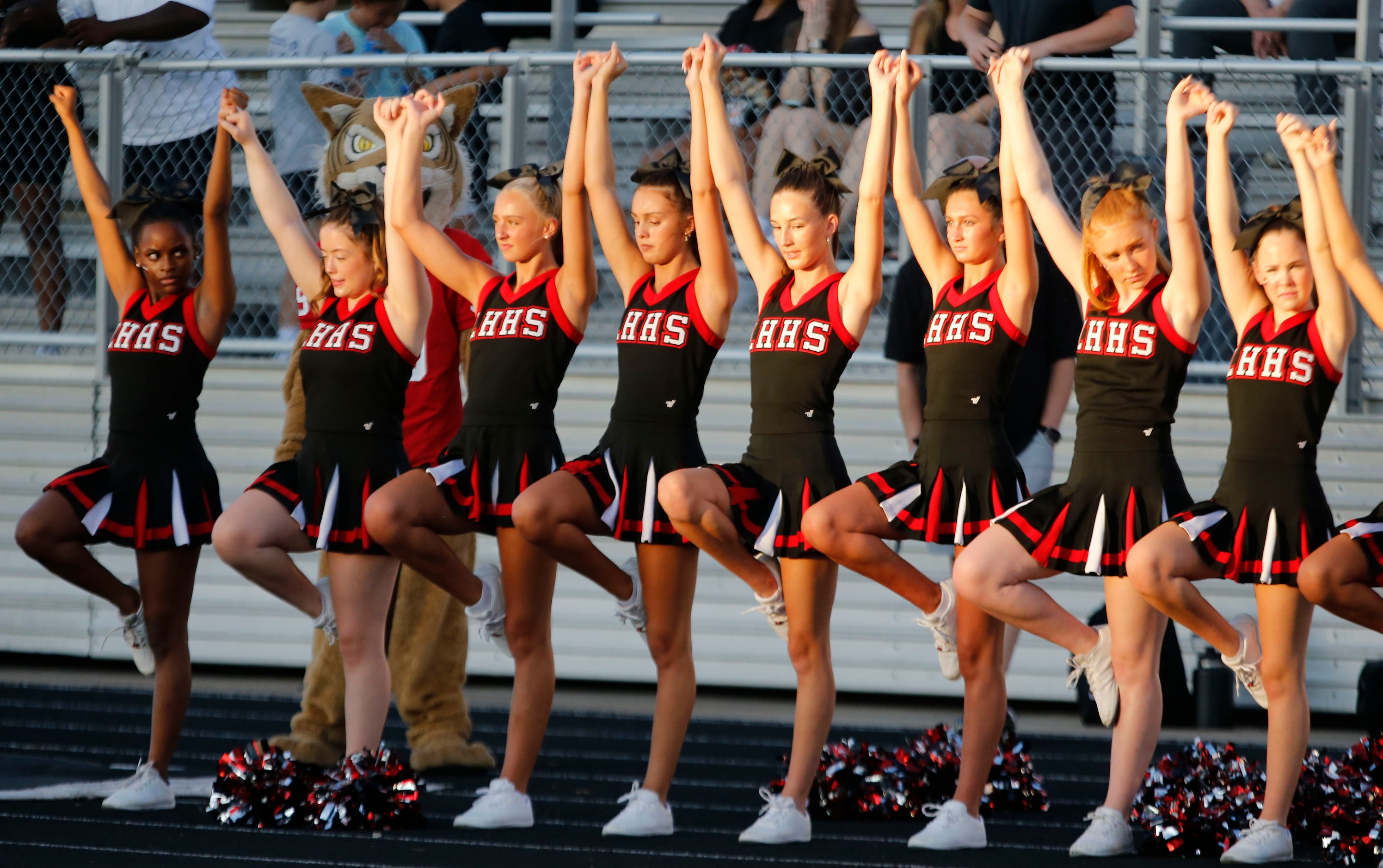 The Lake Highlands cheerleaders hold hands high in the late afternoon sun during a kickoff...