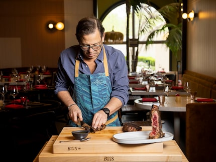 Chef John Tesar carves into a 48-ounce 44 Farms dry-aged porterhouse steak at his new...