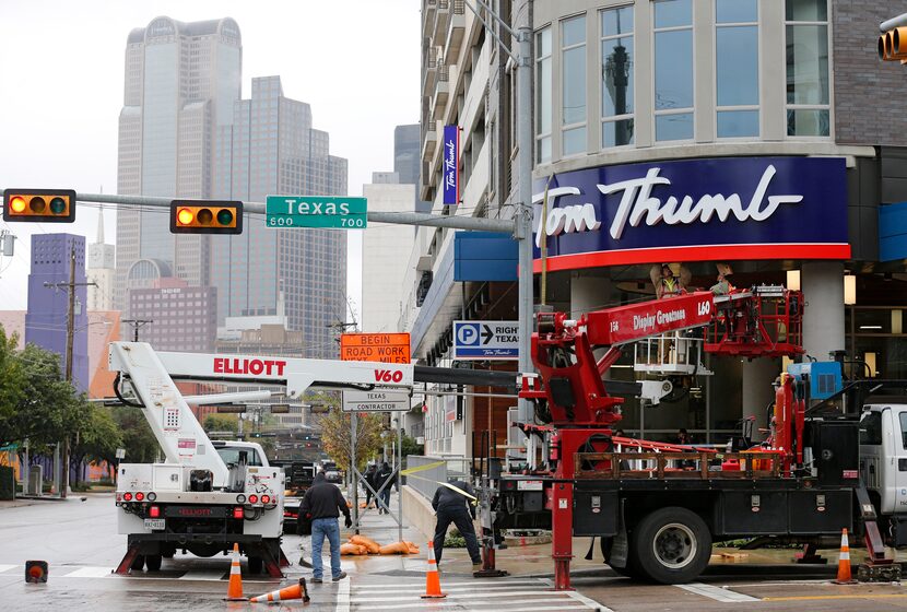 A construction crew works on the sign in front of the Tom Thumb grocery store in downtown...