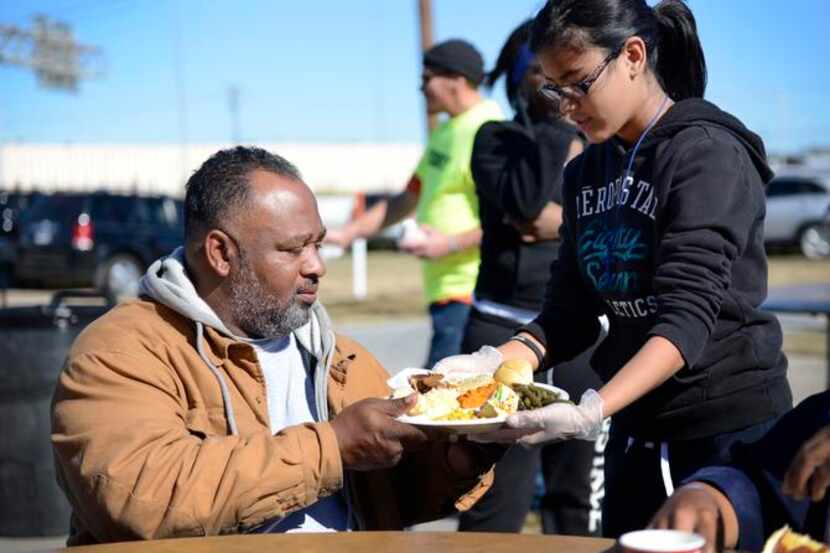
Volunteer Nancy Morataya, 13, hands Howard B. Bates Sr. a plate of food during the...