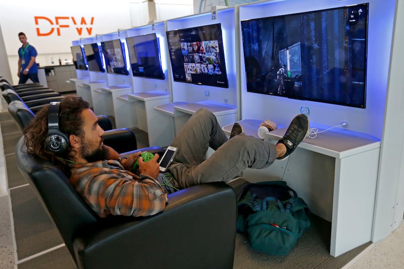 Traveler Conor Sandoval plays a video game at Gameway inside Terminal E of Dallas/Fort Worth...