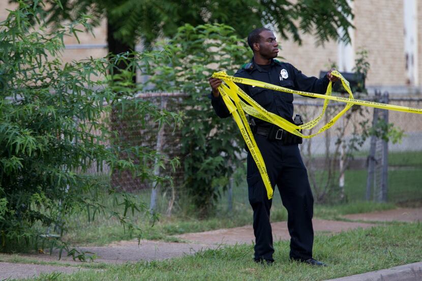 A Dallas police officer tapes off the crime scene involving a shooting in an area near...