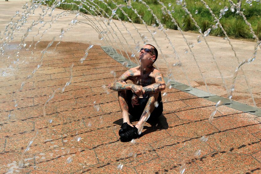 Joshua Peek, 34, of Dallas sits in the middle of one of the fountains at Belo Garden in...