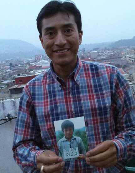 The adult Carlos holds up a photograph of himself as a child in Guatemala.