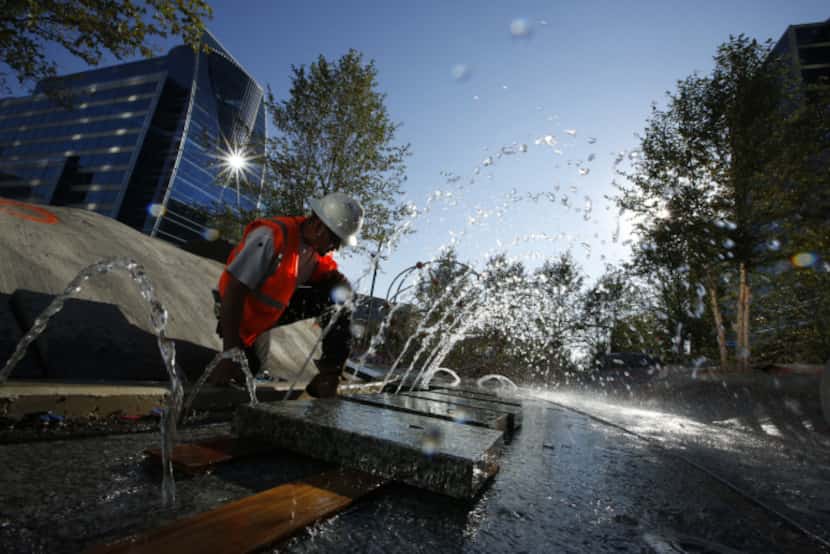 Construction worker Jesus Solorzano tests a water feature at the park. The park represents...
