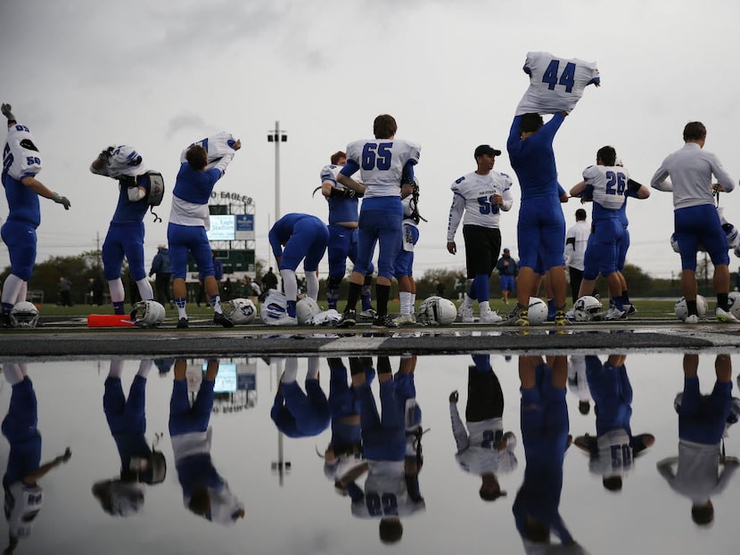 Midlothian players put on their gear in between rain showers before a high school football...