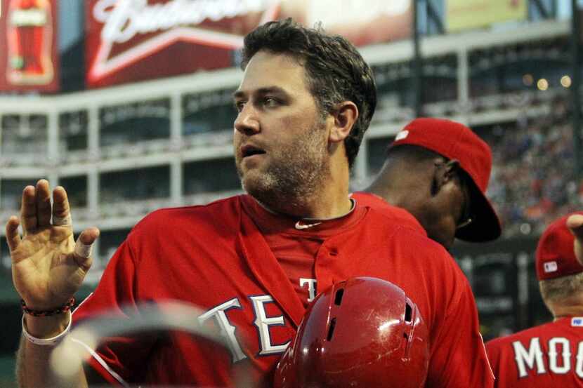 Texas designated hitter Lance Berkman is greeted at the dugout after scoring a run in the...