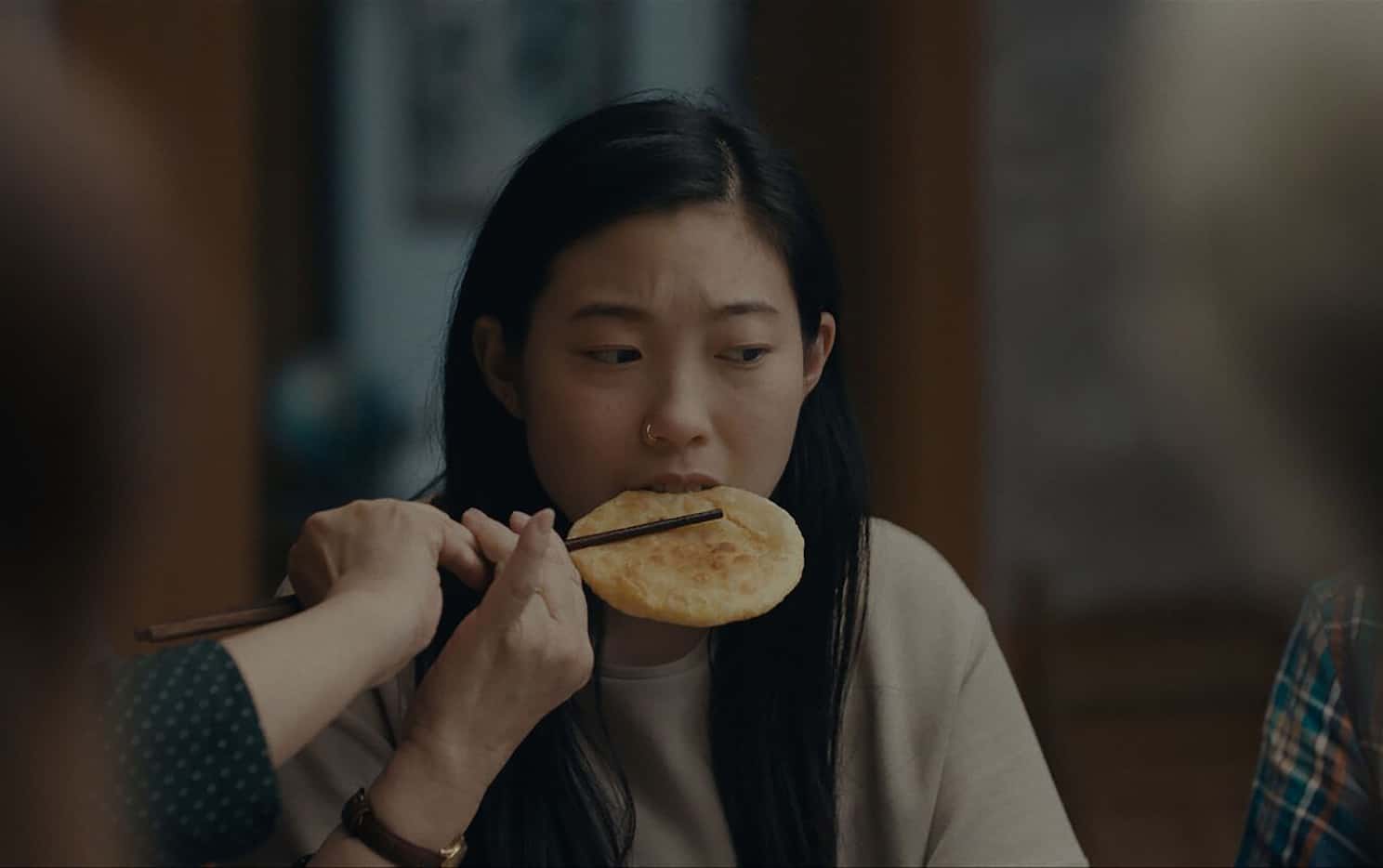 Billi (Awkwafina) accepts food from her grandmother's chopsticks in The Farewell.