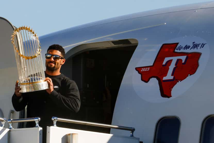 Texas Rangers' Marcus Semien hoists the Commissioner's Trophy upon the arrival of the...