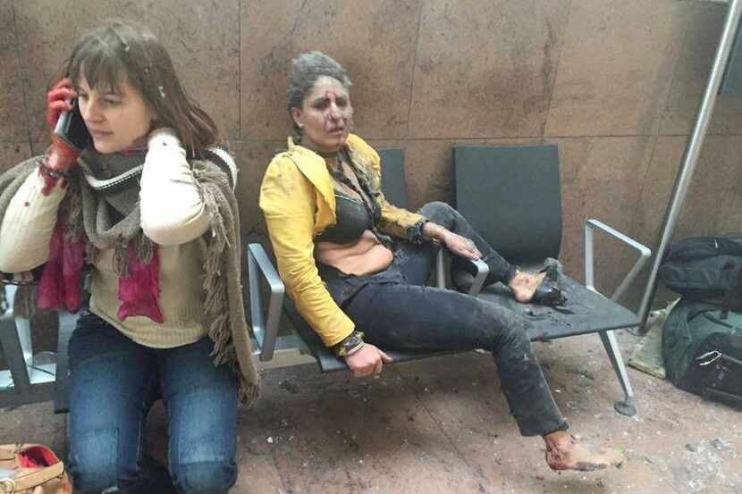 
An injured woman looks on as another speaks on her mobile phone following twin blasts at...
