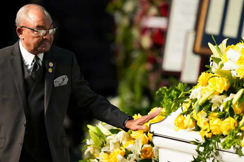 Kirk Johnson reaches out to touch his mother’s casket after speaking during funeral services...
