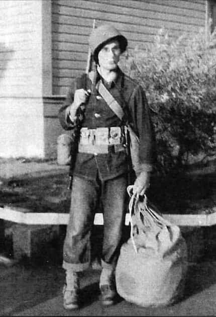 A black and white photo of Clifford A. Stump in his army uniform carrying a bag.