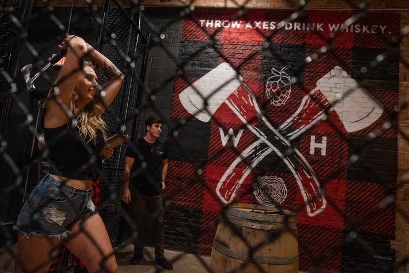 Customers at Whiskey Hatchet throw axes in designated bays. Here, staffer Paige Blaylock...