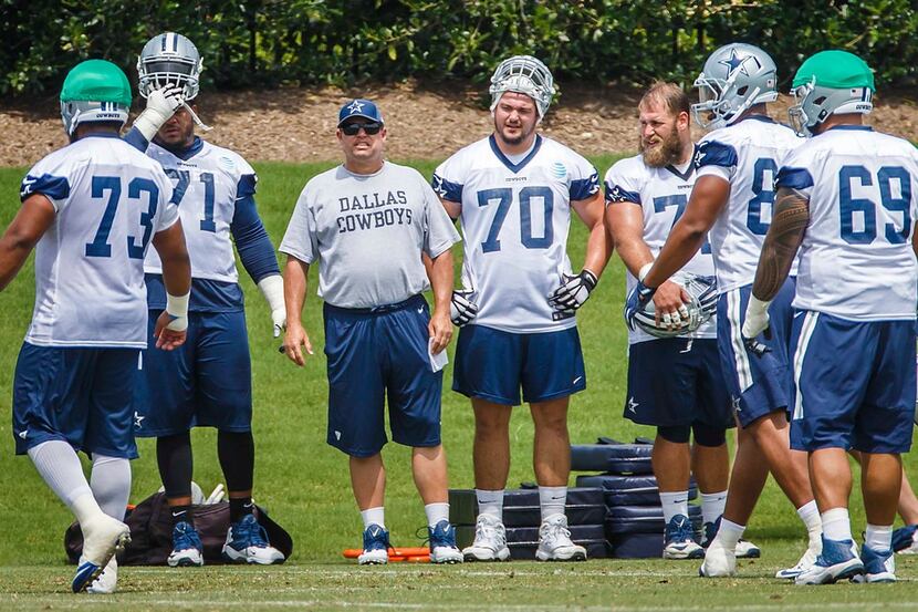 Dallas Cowboys offensive line coach Paul Alexander watches his team workout along side...