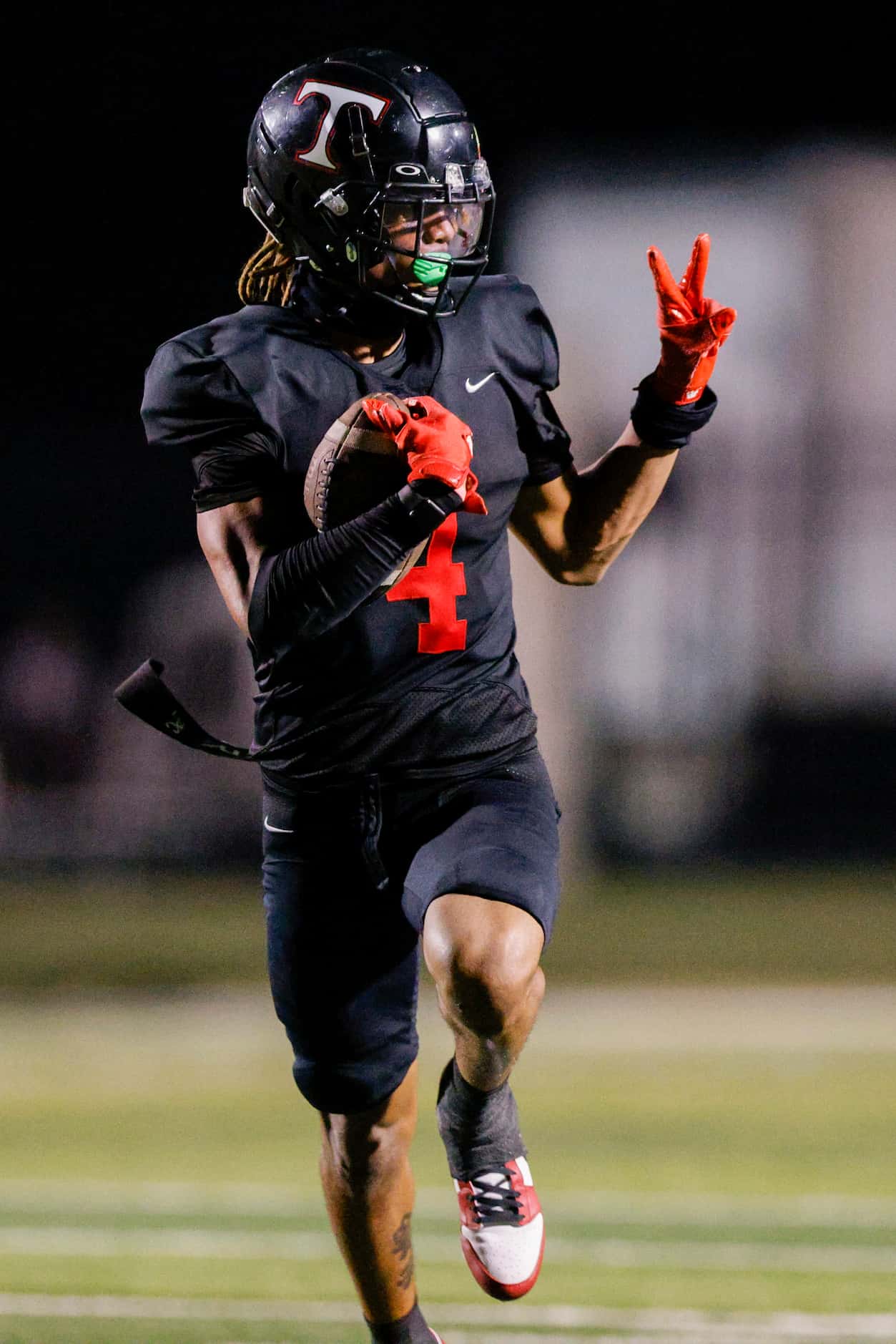 Euless Trinity wide receiver Jarvis Heimuli (4) holds up a peace sign as he runs for a 70...