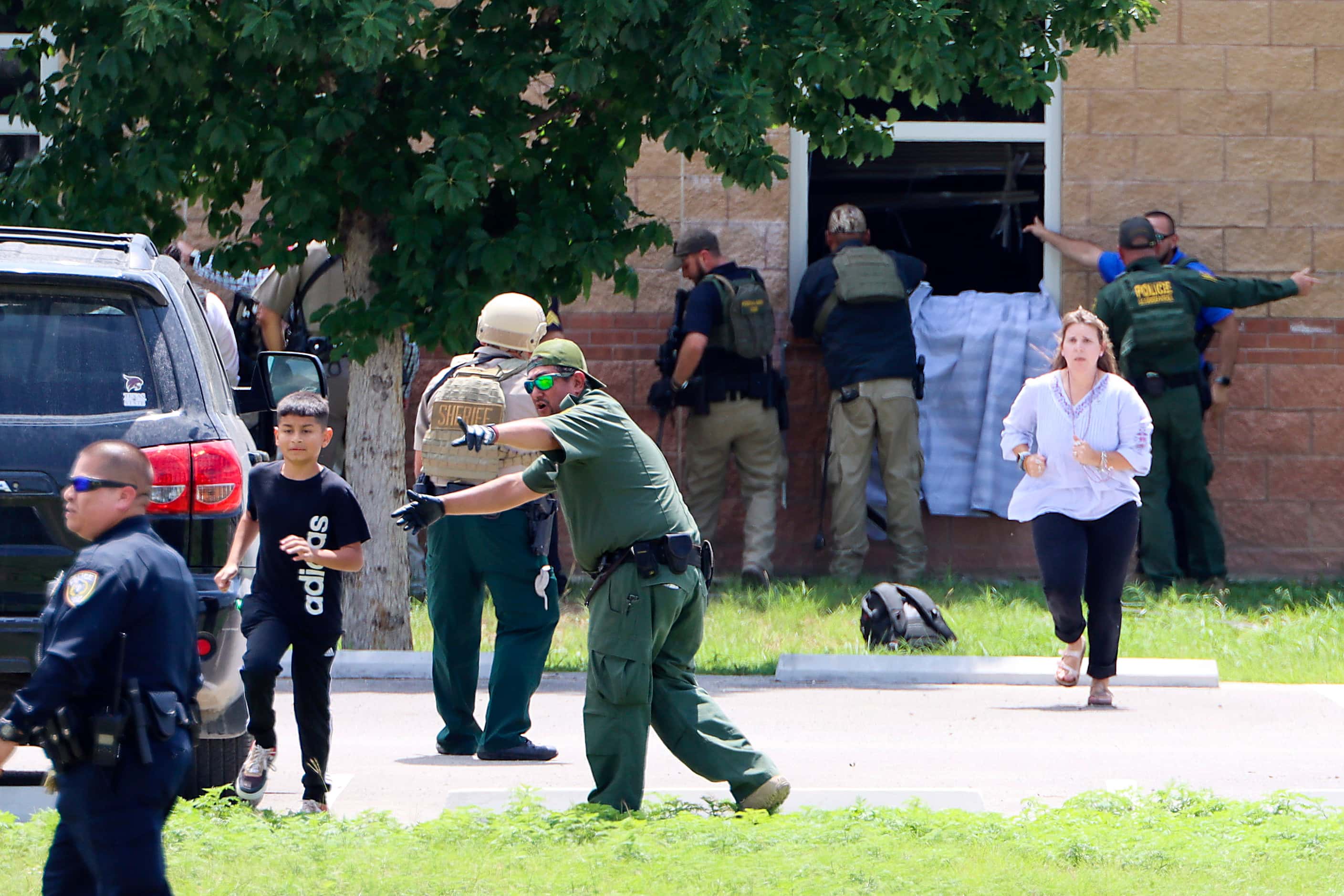 School children are evacuated by law enforcement officers through classroom windows in a...