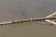 Oil spills into the surrounding waters after a barge hit a bridge near Galveston, Texas, on...