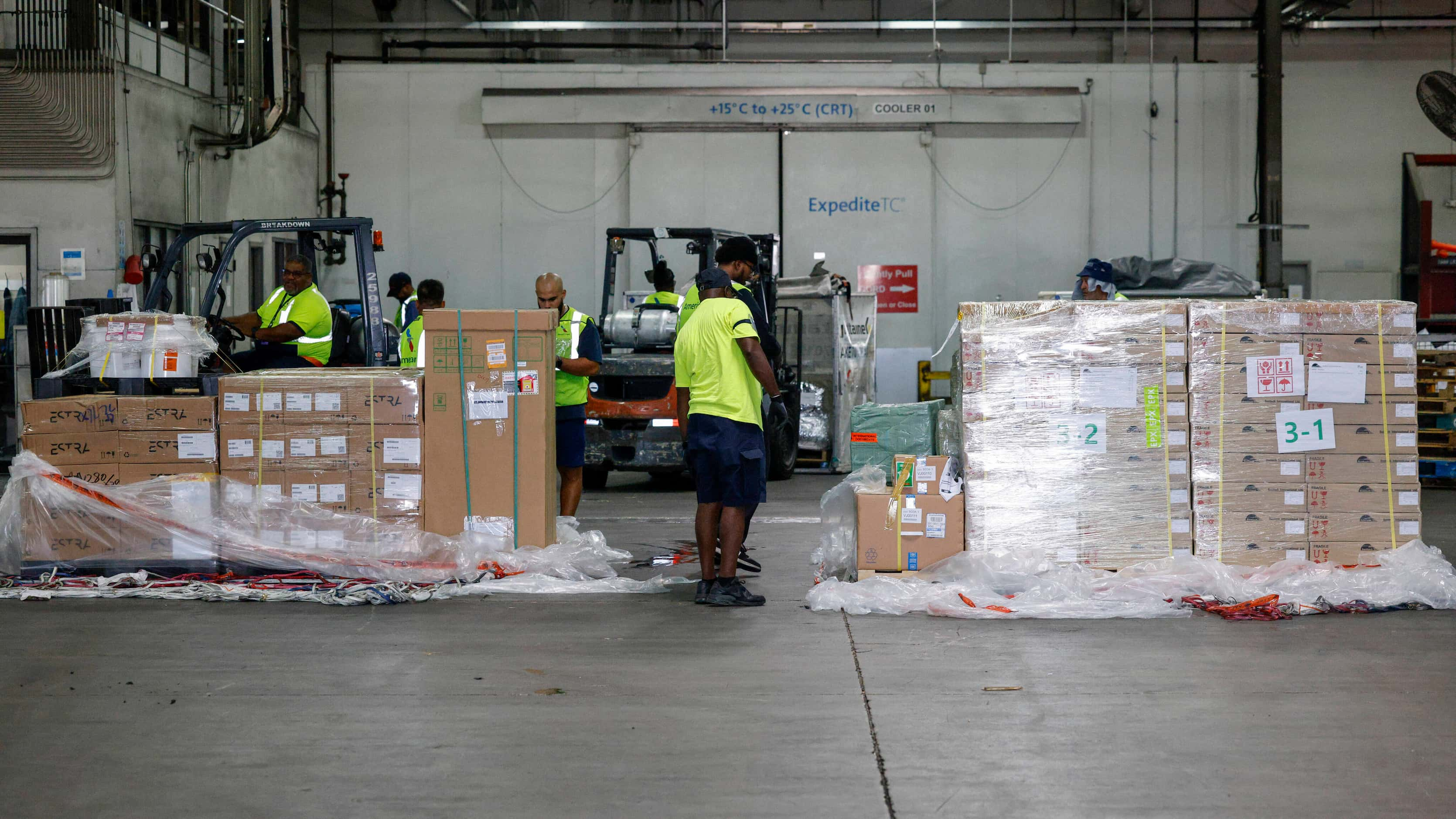 American Airlines cargo workers breakdown incoming cargo at a facility near the airfield,...