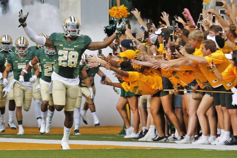Baylor safety Orion Stewart (28) leads the Bears onto the field past a group of cheering...