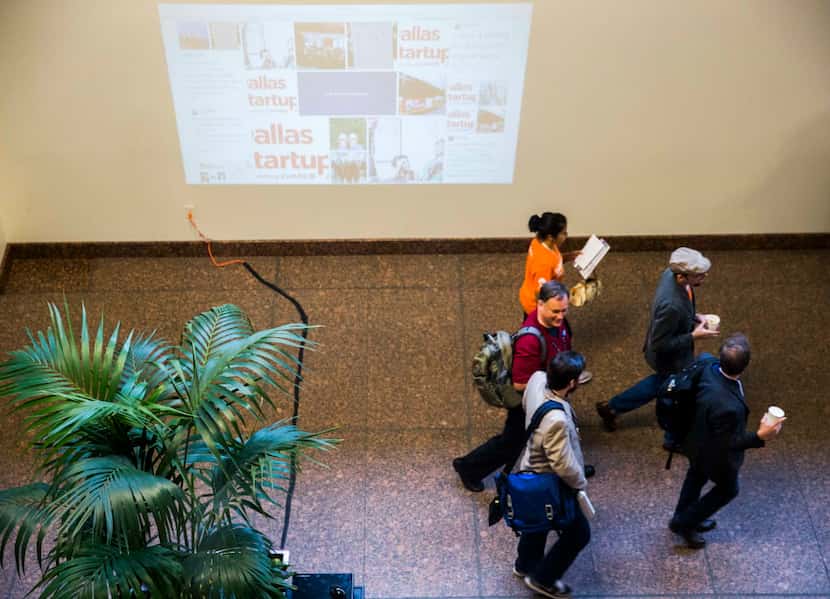 Dallas Startup Week participants walk past a projected social media wall on Tuesday, April...