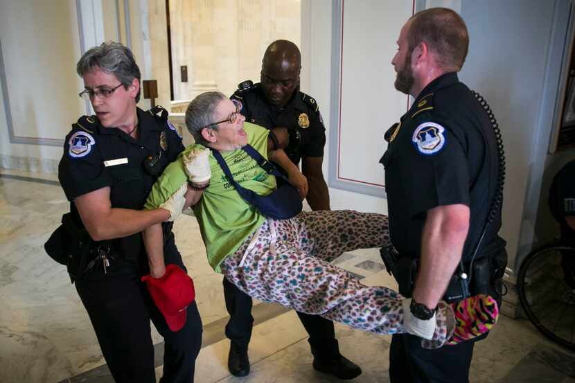 A demonstrator is removed from outside of the offices of Senate Majority Leader Mitch...