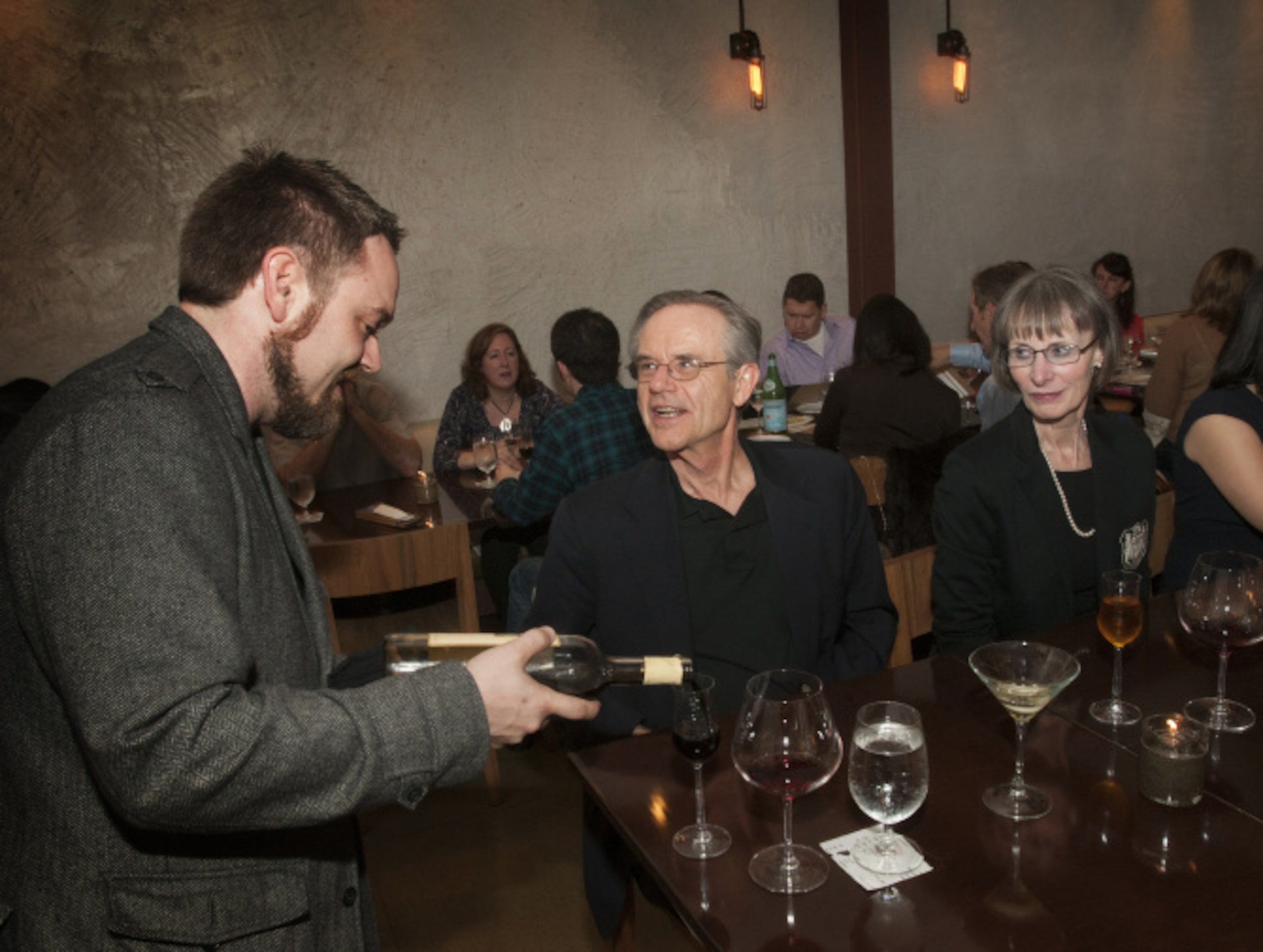 General manager and sommelier Ryan Tedder, left, helps John Neufeld, center, and his wife...