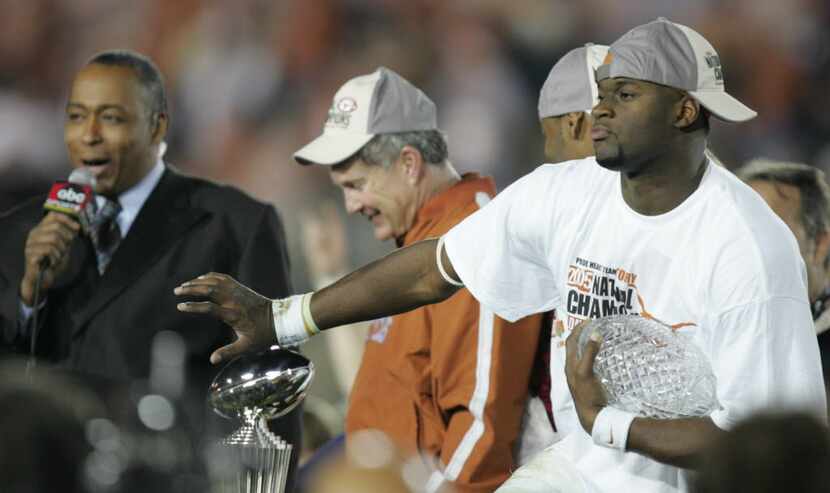Texas Longhorns Vince Young does a Heisman pose with the Championship trophy as head coach...