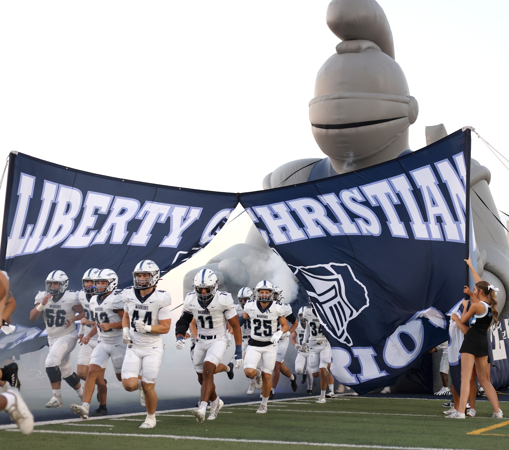 Argyle Liberty Christian players bust through the team sign before the opening kickoff...