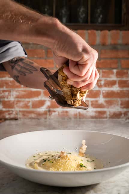 Corporate Chef Ty Thaxton adds finishing touches to a dish of white truffle raviolo with...