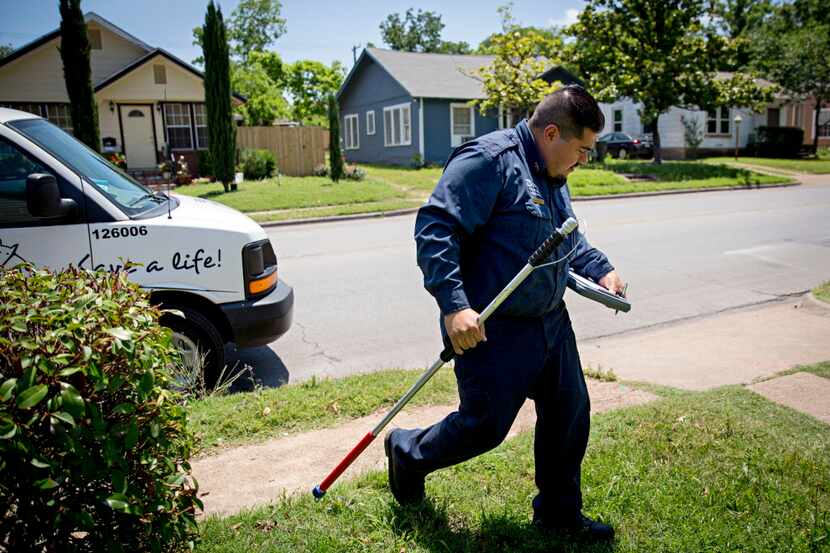 Esteban Rodriguez of Dallas Animal Services looks down at his clipboard to consult a call...