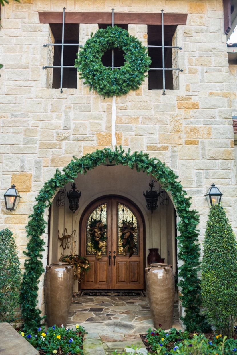 A wide, bold garland on a stone archway, along with a coordinating wreath, creates a...