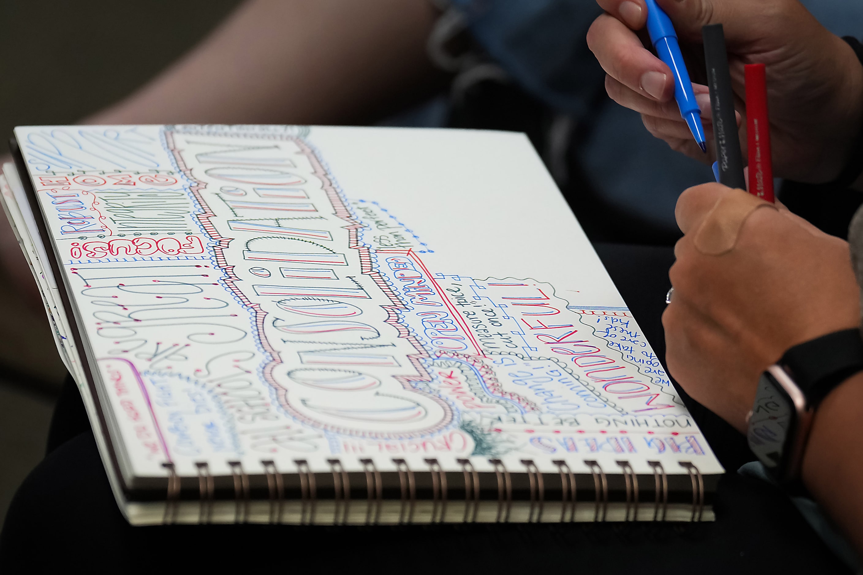 A woman in the audience draws in a sketch pad while listening to discussion of a...