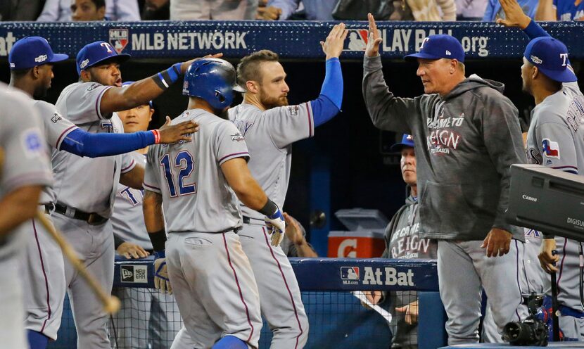 Texas Rangers manager Jeff Banister (28) congratulates Jonathan Lucroy as teammates swarm...