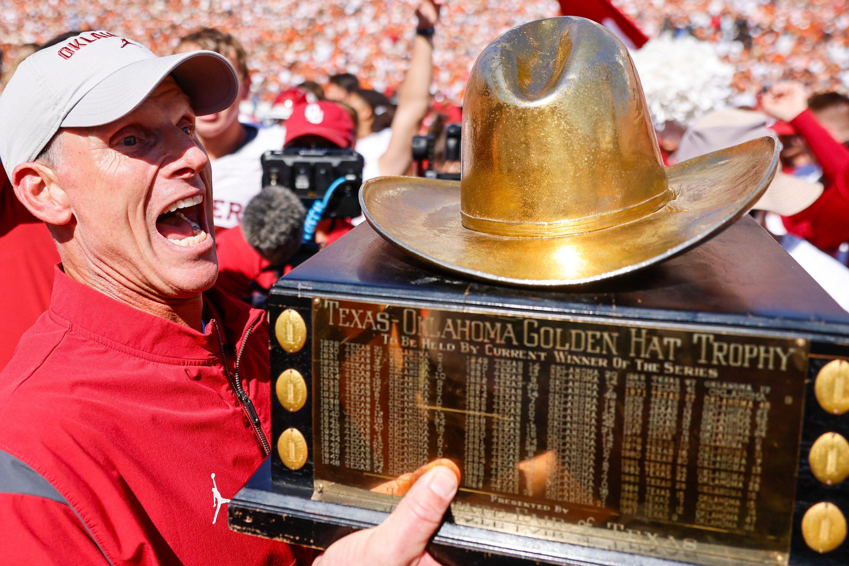 Oklahoma coach Brent Venables cheers holding the trophy after winning the Red River Rivalry...