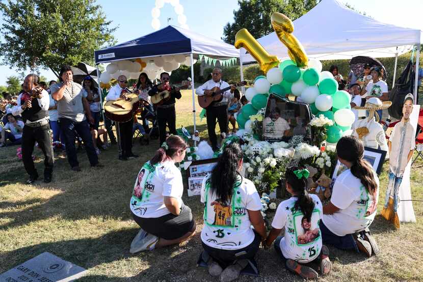 Xavier Gonzalez’s mother, Lluneli, and three sisters sit in front of his grave, Sunday in...