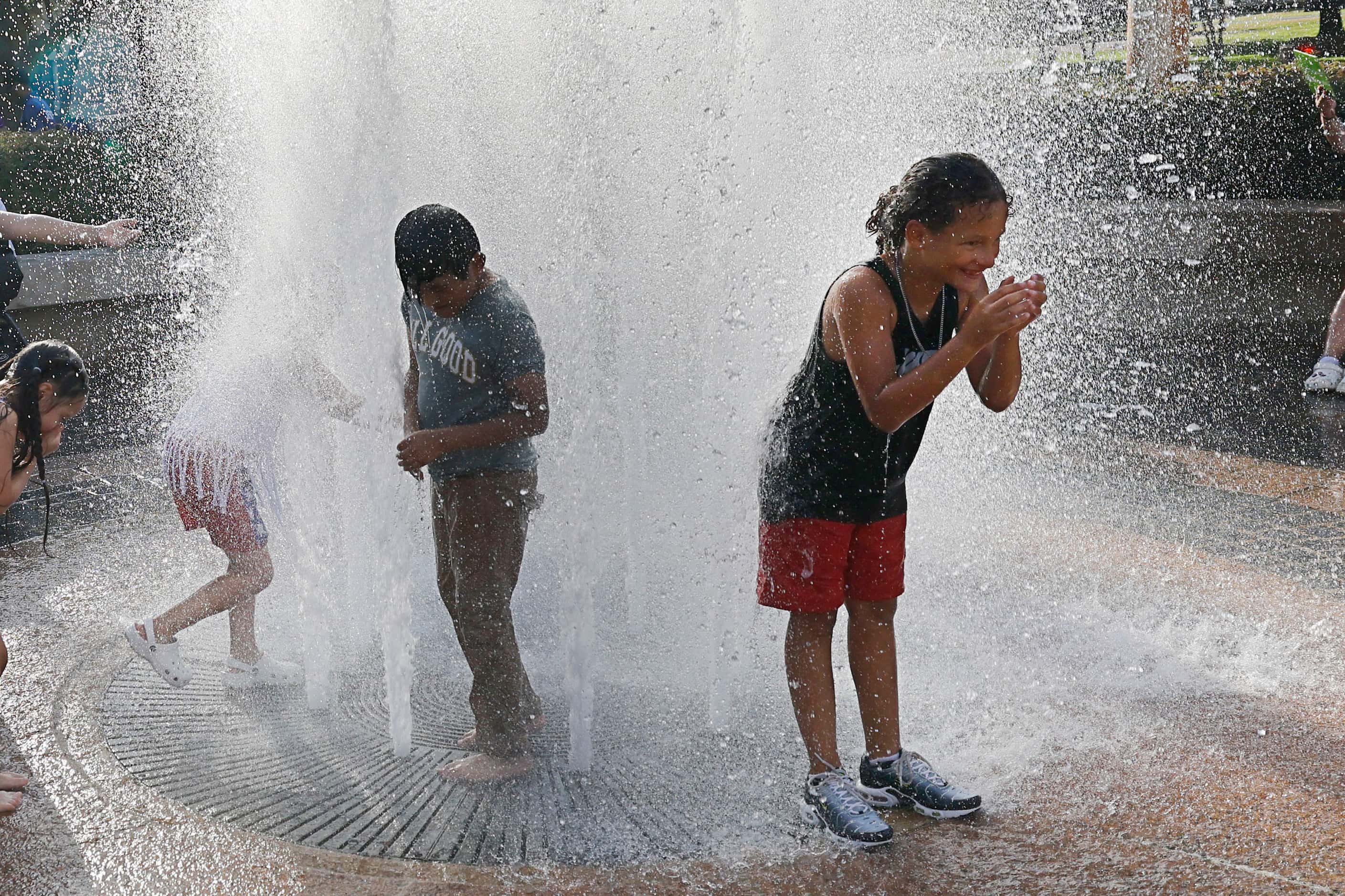 Roman Tapero, 9, of Aurora Calif., right, cools off in a water fountain during the Fair Park...
