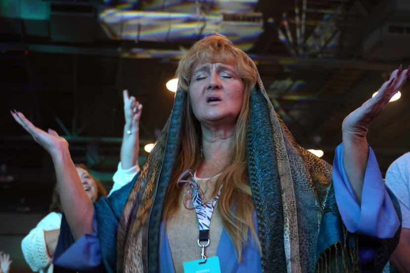 Sporting a costume of Mary Magdalene, Tracy Mehne of Rowlett, raises her hands as the...