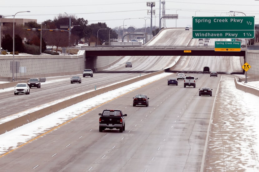 Drivers travel along the Dallas North Tollway near Spring Creek Parkway as snow covers parts...