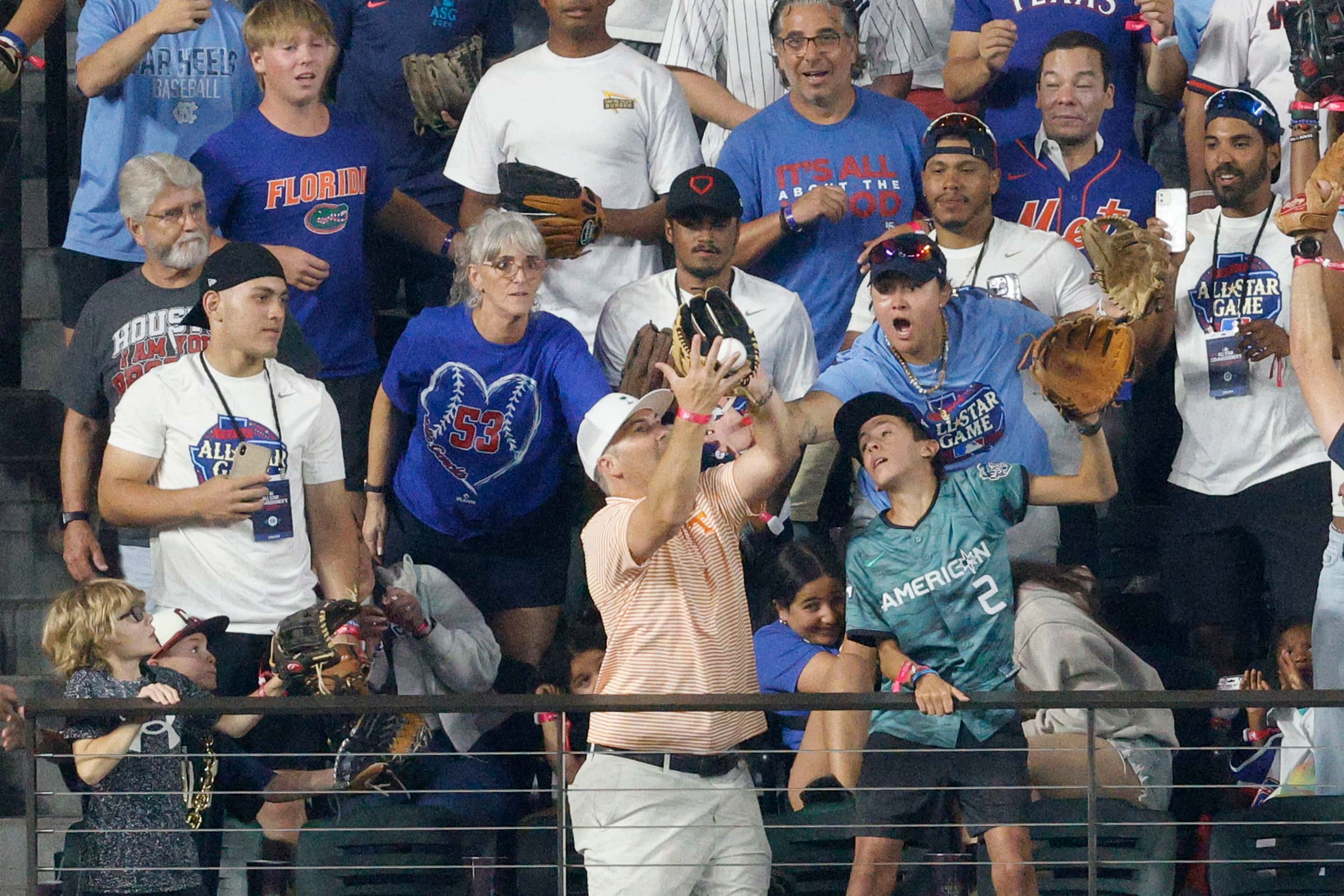 A fan catches a home run ball hit by American League's Adolis Garcia, of the Texas Rangers,...