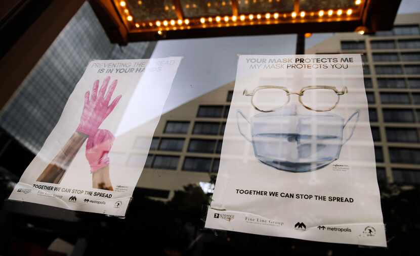 Signs in Sundance Square business windows remind people to wear a mask and control the...